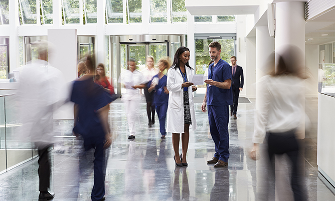 doctor and nurse isolated amongst busy hospital corridor